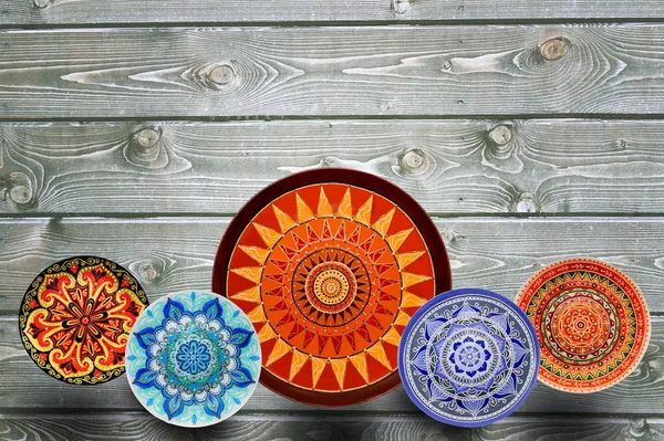 Set dekorativer Keramikteller mit handbemalten Punktmustern und Acrylfarben auf grauem Holzgrund. Kopierraum. — Stockfoto