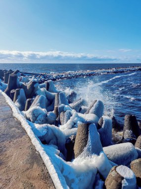 Real photograph of a pier stretching into the sea in early spring. Calm water, cool tones, and authentic coastal atmosphere.