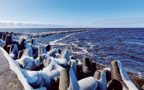 Real photograph of a pier stretching into the sea in early spring. Calm water, cool tones, and authentic coastal atmosphere.