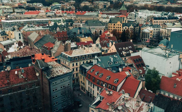 Rigas Old Town 'daki binaların çatılarını gösteren gerçekçi bir fotoğraf. Görüntü, mimari ayrıntıları, değişik çatı şekillerini ve şehrin doğal ışıklandırma altındaki tarihi cazibesini yakalıyor..