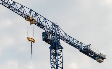 A tall tower crane rising high into the sky at a construction site, symbolizing the power of modern engineering and the dynamic progress of the building process in an urban environment. 