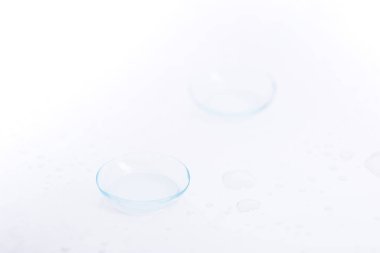 Beyaz arkaplanda damlaları olan iki kontak lens.