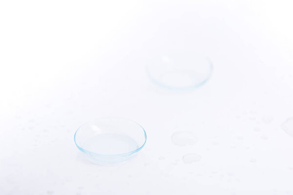 Two contact lenses close-up on white background with drops.