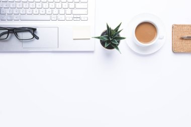 Dizüstü bilgisayarı, kahvesi ve ofis malzemesi olan bir iş yeri. Kopyalama alanı ile.