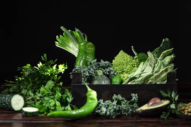 Tahta bir kutuda, koyu ahşap arka planda taze sebzelerin çeşitliliği..