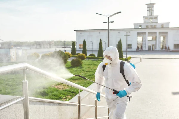 For health and environment. Sanitization, cleaning, disinfection of the streets and alleys in the city center due to the emergence of the Covid19 virus. Man in protective suit and mask at work — Stock Photo, Image