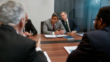 Dikkatlice dinliyorum. Çok kültürlü iş adamları modern ofiste toplantı yaparken yeni projeleri tartışıyor. İş adamları birlikte çalışıyor.