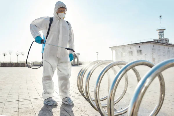 The clean you expect. Sanitization, cleaning, disinfection of the streets and alleys in the city center due to the emergence of the Covid19 virus. Man in protective suit and mask at work — Stock Photo, Image