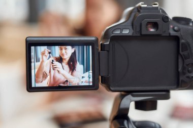 Seyircinin ihtiyaçları için. Asyalı kadın blogcu kozmetik ürünleri gösteriyor. Güzellik blogu için evde kamera kullanarak özel bir video kaydediyor.