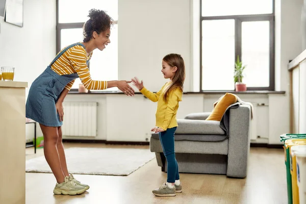 Nice to meet you. African american woman baby sitter get acquainted with caucasian cute little girl. They are standing indoors and talking — Stock Photo, Image