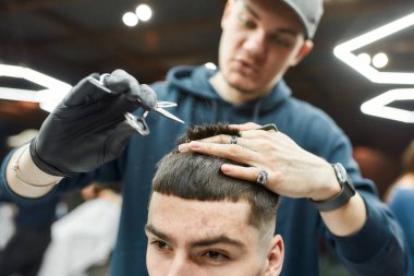 Saçını kestiriyorum. Berber dükkanında çalışırken saç kesimi ve tarak tutan profesyonel berber. Seçici odak