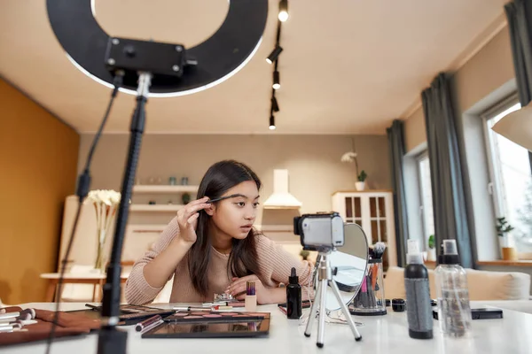 Szépségfogadás. Ázsiai női blogger bemutató kozmetikai termékek és smink ecset, miközben rögzíti a bemutató videó neki szépség blog segítségével kamera otthon — Stock Fotó