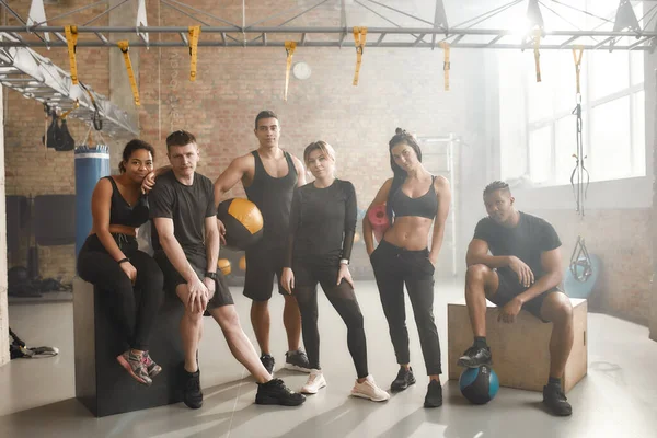 Siyah spor giyim giymiş bir grup sporcunun endüstriyel spor salonunda dikilirken kameraya baktığı uzun bir çekim. Grup eğitimi, takım çalışması konsepti — Stok fotoğraf