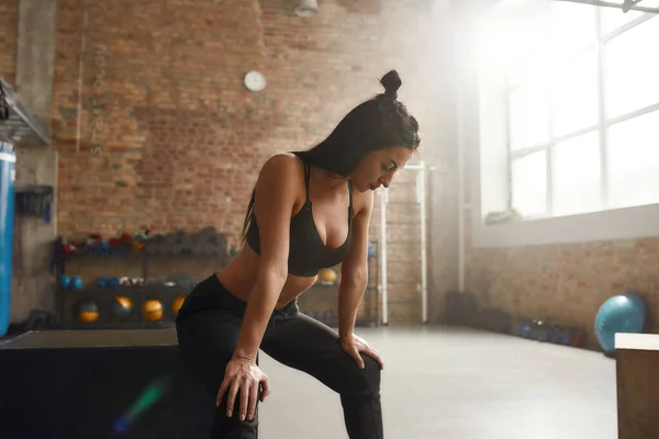 Harika bir vücuda ulaşmak. Siyah spor giyim giymiş sportif bir kadın endüstriyel spor salonunda egzersiz yapıyor. — Stok fotoğraf