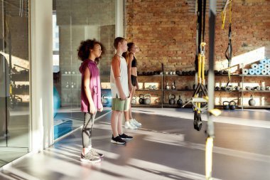 Sabah sporu. Üç gencin tam boy çekimi. Beden eğitimi öncesi ısınma hareketleri. Spor, sağlıklı yaşam tarzı, aktif çocukluk konsepti