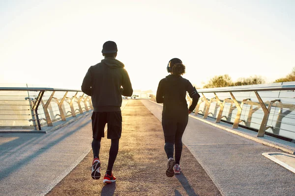 Καλό τρέξιμο. Πίσω όψη του σπορ αφρικανικό ζευγάρι τζόκινγκ μαζί στη γέφυρα νωρίς το πρωί. Ζεστό φως. Άντρας και γυναίκα τρέχουν έξω. Πλήρες μήκος — Φωτογραφία Αρχείου