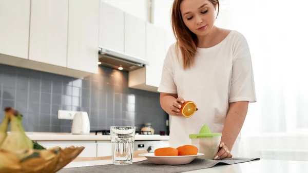 Beginnen Sie Ihren guten Morgen. Schnappschuss einer jungen kurvigen Frau, die eine Orange hält, während sie in der Küche frischen Orangensaft zubereitet — Stockfoto