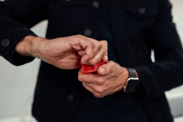 Närbild på händerna. Man använder röd marijuana kvarn, när man står i köket. Cannabis och ogräslegalisering — Stockfoto