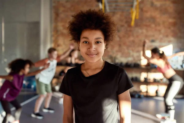 Più forte e più intelligente. Ritratto di un ragazzo che sorride alla telecamera prima di riscaldarsi, allenandosi insieme ad altri bambini e allenatori in palestra. Sport, stile di vita sano, concetto di infanzia attiva — Foto Stock