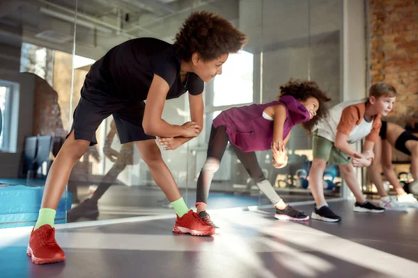 Unisciti a noi per vedere i risultati. Ritratto di un ragazzo che sorride mentre si scalda, mentre si allena insieme ad altri bambini in palestra. Sport, stile di vita sano, concetto di infanzia attiva — Foto Stock