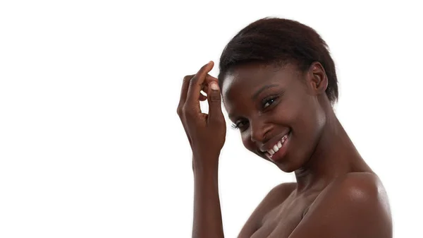 Чарівна краса. Портрет молодої і веселої африканської жінки, яка дивиться на камеру і посміхається, стоячи на білому тлі — стокове фото