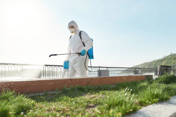 For living healthy. Sanitization, cleaning and disinfection of the city due to the emergence of the Covid19 virus. Specialized team in protective suits and masks at work near the riverside — Stock Photo, Image