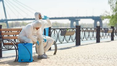 Tükenmiş. Covid19 virüsünün ortaya çıkmasından dolayı şehrin temizlenmesi, temizlenmesi ve dezenfekte edilmesi. Koruyucu giysi ve maskeli özel ekip nehir kenarında mola verdi.