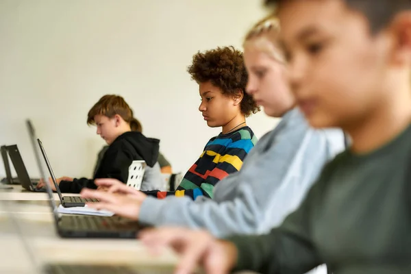 Belépünk, hogy tanuljunk, hagyjuk, hogy elérjük. Portré afro-amerikai iskolás fiú nézi a képernyőn a laptop együtt más diákokkal egy lecke során a modern okos iskola — Stock Fotó