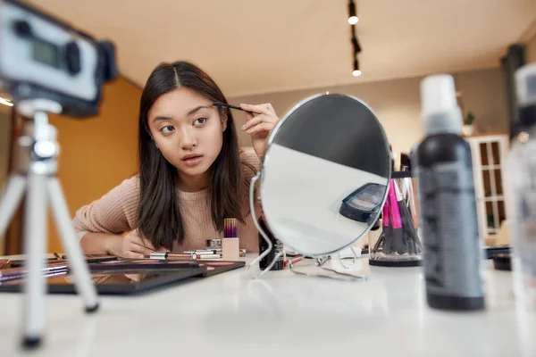 Se bra ut. Asiatiska kvinnliga bloggare testa kosmetiska produkter och sminkborstar samtidigt spela in en tutorial video för hennes skönhet blogg med kameran hemma — Stockfoto