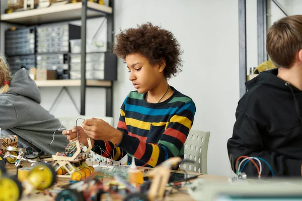 Explorando novas possibilidades. Um miúdo afro-americano numa aula de robótica a fazer o seu próprio veículo. Crianças inteligentes e educação STEM . — Fotografia de Stock