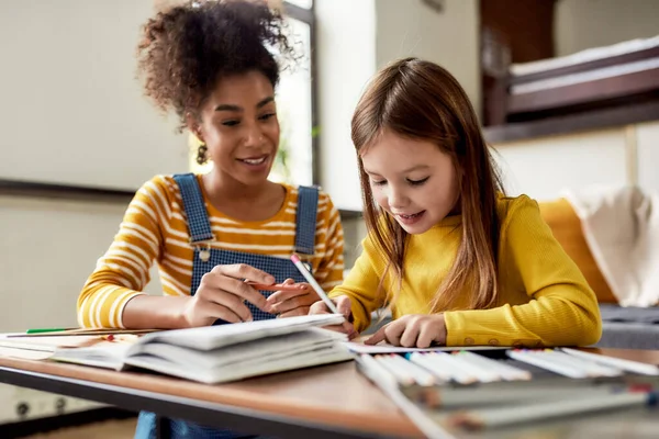 Para a Infância Feliz. Menina caucasiana passando tempo com babá afro-americano. Eles estão desenhando, aprendendo a escrever cartas — Fotografia de Stock