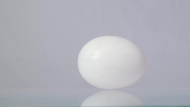 Feliz Páscoa. Ovo de galinha branca girando e rolando em um fundo branco com bela reflexão — Vídeo de Stock