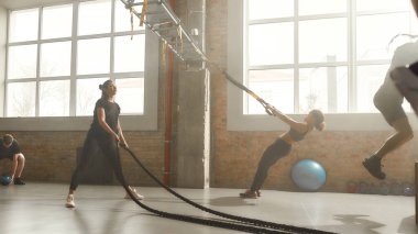 Fit için daha çok teşvik et. Endüstriyel spor salonunda spor yapan insanların tam boy çekimi. Grup eğitimi, takım çalışması konsepti