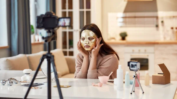 Trying new things. Young female blogger recording a tutorial video for her beauty blog about skincare routine. Vlogger testing face mask, recording video for social network