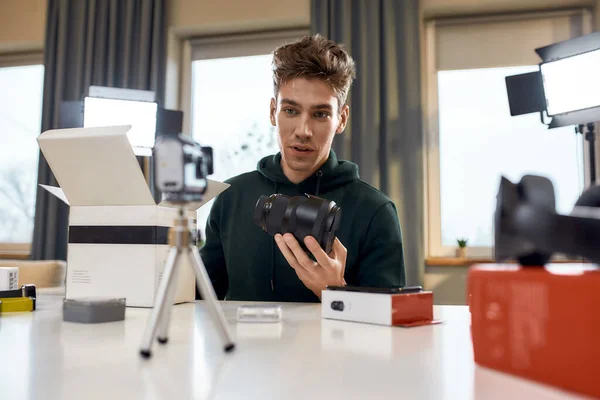 Especialista em Qualidade. Jovem blogueiro de tecnologia masculina gravando vídeo blog ou vlog sobre novas lentes de câmera em estúdio em casa. Blogging, Trabalho a partir do conceito Home — Fotografia de Stock