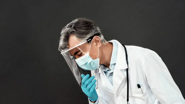 Covid19 'u durdurun. Tıbbi maskeli, mavi eldivenli, koyu arkaplanda duran olgun bir erkek doktorun yan görüntüsü. — Stok fotoğraf