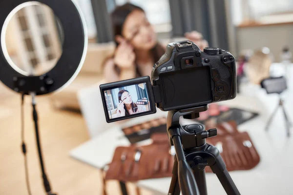 Engage with the world. Asian female blogger applying makeup while recording a tutorial video for her beauty blog using camera at home — Stock Photo, Image