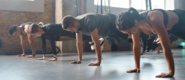 Acı yoksa, kazanç da yok. Spor salonundaki spor salonlarında spor yaparken vücut esneme hareketleri yapan sporcu erkekler ve kadınlar. Kayışlar, grup çalışması konsepti