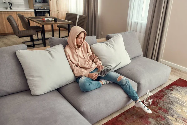 Difficile de se concentrer. Jeune femme caucasienne assise sur le canapé à la maison, essayant d'utiliser un ordinateur portable après avoir fumé de la marijuana d'un bong ou d'un tuyau d'eau en verre — Photo