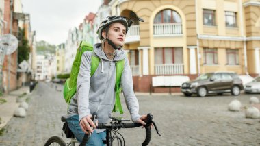 Kasklı, termal çantalı ya da sırt çantalı genç bir teslimatçı şehirde bisiklet sürüyor, yiyecek getiriyor. Kurye, teslimat hizmeti konsepti