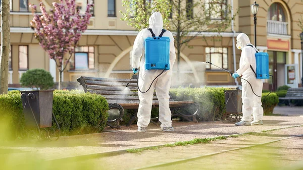 Stop disease in its tracks. Sanitization, cleaning, disinfection of streets and alleys in the city due to the emergence of the Covid19 virus. Specialized team in protective suits and masks at work — Stock Photo, Image