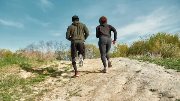 Corsa campestre. Vista posteriore di coppia fitness in abbigliamento sportivo correre insieme all'aria aperta nella natura. Formazione all'aperto — Foto Stock