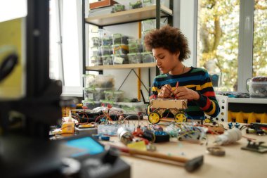Passion in Every Work. Child programming, testing robot vehicle, working with wires and circuits at stem class.