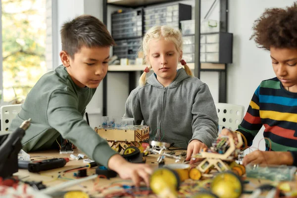 Il futuro è in costruzione. Tre bambini che costruiscono robot e veicoli alla lezione di robotica. Bambini intelligenti e istruzione STEM . — Foto Stock