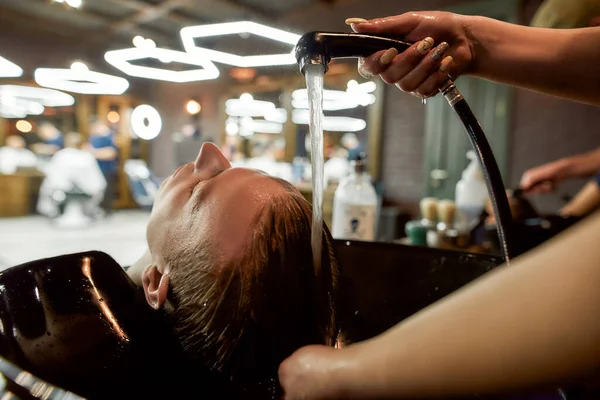 Giornata di bellezza. Primo piano di un barbiere che lava capelli di clienti prima di un taglio di capelli. Giovane ragazzo in visita moderno barbiere o salone di bellezza — Foto Stock