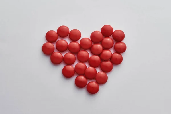 Top view of heart made of red pills on light background. Medications, drugs for heart disease concept — Stock Photo, Image