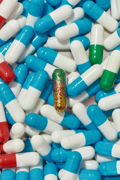 Horní pohled na zelené zlaté třpytky pilulky ležící ve středu mezi jinými medicínskými pilulky, kapsle ležící náhodně. Zdravotní péče, vitamíny a koncepce léčby — Stock fotografie