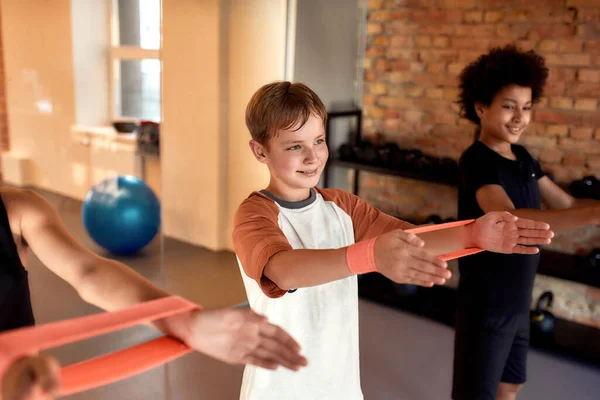 Biały chłopak ćwiczący razem z innymi dzieciakami na siłowni. Sport, zdrowy styl życia, wychowanie fizyczne — Zdjęcie stockowe