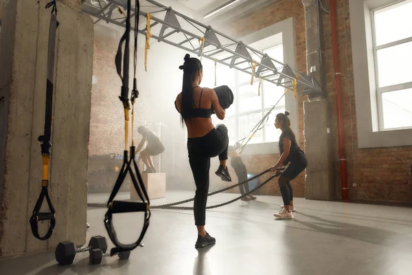 Deixa os corpos caírem no chão. Tiro completo de pessoas esportivas fazendo exercícios no ginásio industrial. Formação em grupo, conceito de trabalho em equipa — Fotografia de Stock