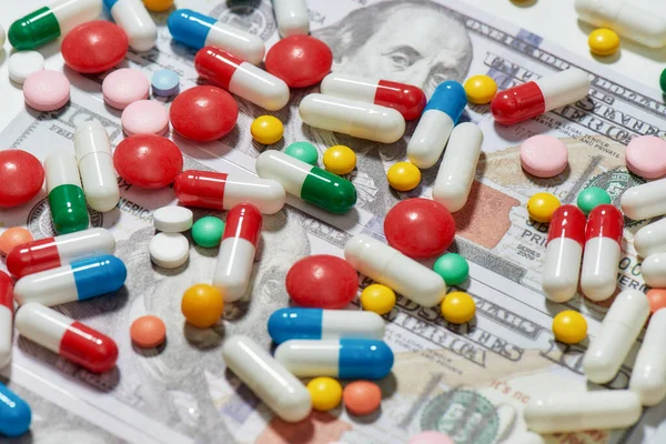 Diferentes pastillas, cápsulas esparcidas por el dinero, fondo de dólar. Atención médica, concepto de tratamiento caro — Foto de Stock